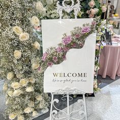 a welcome sign in front of a floral display at a flower shop with roses and other flowers