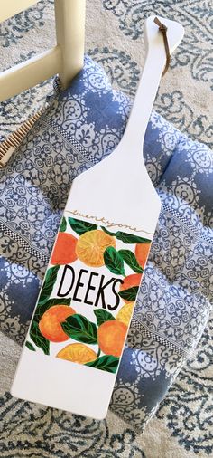 a bottle shaped like a spoon with the word decks painted on it sitting on a blue and white patterned chair