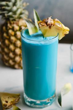 a blue drink with a pineapple garnish on the rim