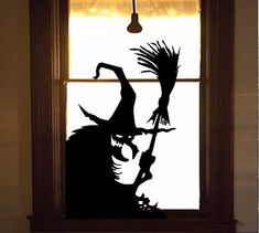 a window with a silhouette of a witch holding a broom