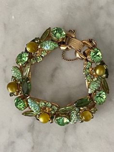 "This is a verified DeLizza & Elster Juliana bracelet. It can be seen in Ann Pitman's Juliana jewelry reference book and it's sought after and rarely seen. It was first seen in 1962. Verified on the isitjuliana website where one can find the companion brooch. Mr DeLizza referred to it as \"corn kernel\" or molded navette. It's dimensional and complete with olivine baubles, open back navettes, marquise and chatons. Put it altogether and you have this wonderful designer bracelet. The bracelet is 7 Vintage Jubilee Bracelet For Evening, Vintage Green Evening Jewelry, Retro Green Bracelet Jewelry, Retro Green Jewelry For Evening, Vintage Green Jubilee Bracelet, Mid-century Green Formal Jewelry, Retro Jeweled Bracelets For Formal Occasions, Retro Jeweled Bracelet For Formal Occasions, Vintage Green Bracelets For Party