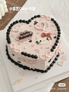 a heart shaped cake with hello kitty decorations on it's top and the words happy birthday written in chinese