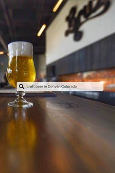 a glass of beer sitting on top of a wooden table