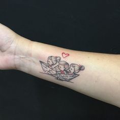 a woman's arm with a small tattoo of two people in a paper boat