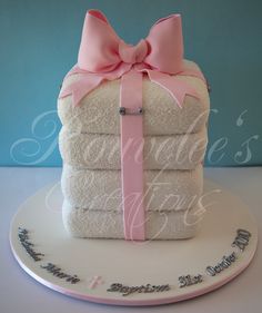 a stack of folded towels on top of a white plate with a pink ribbon tied around it