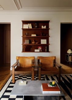 a living room with two leather chairs and a coffee table in front of a bookshelf