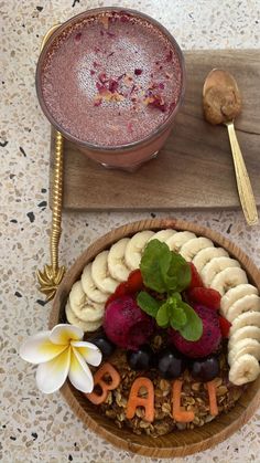 a bowl of fruit, nuts and other food on a table next to a spoon