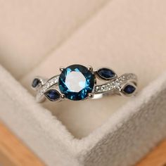 a blue and white diamond ring in a box with its lid open to show it's inside