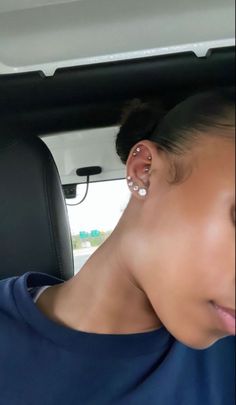 a woman with ear piercings in the back seat of a car