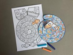 a coloring book and plate on a table with colored crayons next to it