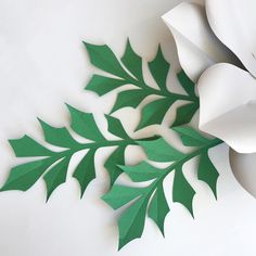 paper flowers and leaves on a white surface