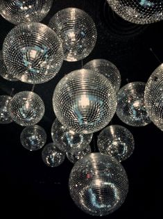 many clear glass balls hanging from the ceiling in a room with black walls and flooring