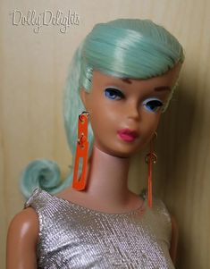 a barbie doll with green hair and orange earrings