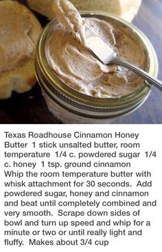 a jar of peanut butter sitting on top of a table next to some bread rolls