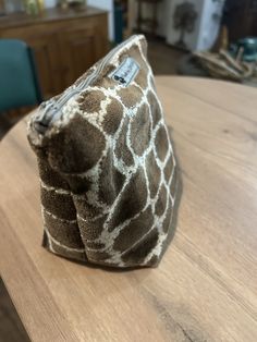 a giraffe print pouch sitting on top of a wooden table