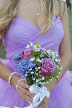 a woman in a purple dress holding a bouquet of flowers