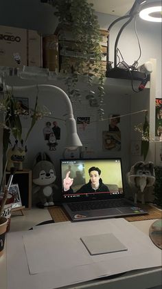 an open laptop computer sitting on top of a desk in front of a plant filled wall