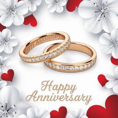 two wedding rings on top of each other in front of flowers with the words happy anniversary