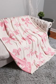 a pink and white blanket sitting on top of a bed next to a black table