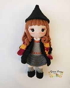 a crocheted doll is wearing a hat and coat, standing against a white background