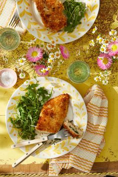 two plates filled with food on top of a yellow and white table cloth next to silverware