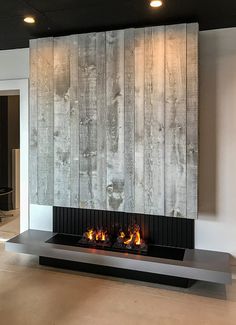 a fire place in the middle of a room with wood paneling on the wall