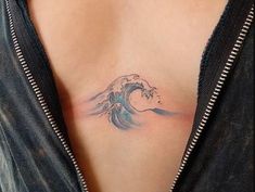 a woman's chest with a wave tattoo on her left side ribcage