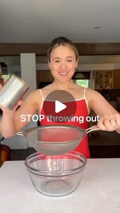 a woman holding a strainer over a glass bowl