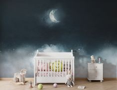 a baby's room with a crib, dresser and wall mural in the background