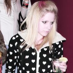 a woman in black and white jacket holding a drink