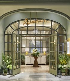 the entrance to an elegant hotel with flowers in vases and potted plants on either side