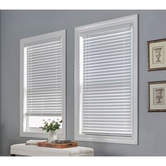 two windows with white wooden blinds in a gray room, one is open and the other has flowers