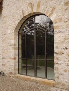 an arched window on the side of a stone building with a bicycle parked in front