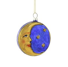 a blue and gold ornament with a face on the moon hanging from a chain