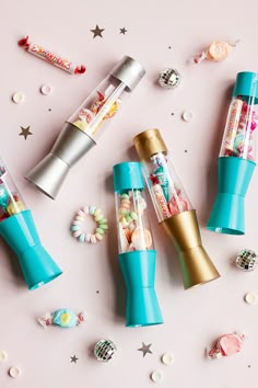 three different types of candy in plastic tubes on a pink surface with stars and confetti