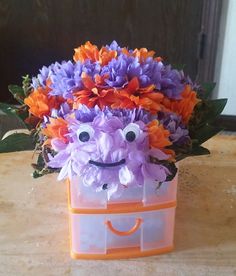 an orange and purple flower box with flowers in the shape of a face on it