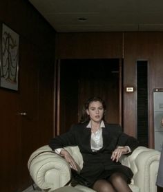 a woman sitting in a chair next to a refrigerator