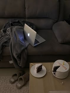 an open laptop computer sitting on top of a table next to a piece of cake