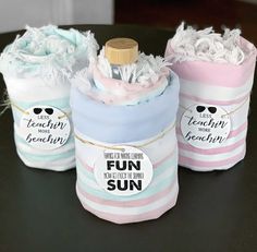 three baby shower products sitting on top of a black table with white and pink stripes