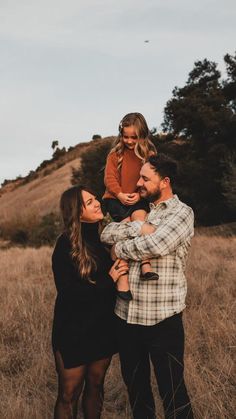 a family standing in a field with their child on their shoulders