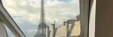 a cat sitting on the window sill looking out at the eiffel tower