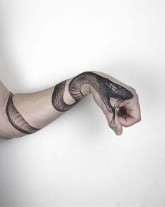 a man's arm with a snake tattoo on it, holding his hand out to the side