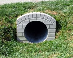 a brick tunnel in the middle of some grass