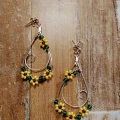 two pairs of earrings with yellow and green beads on wooden floor next to brick wall