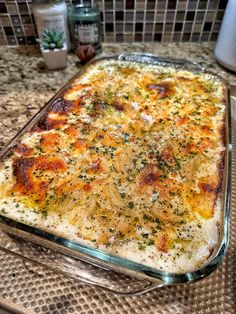 a casserole dish with cheese and herbs in it sitting on a counter top