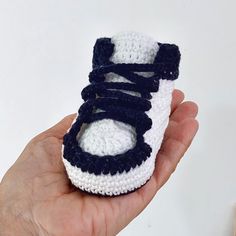 a hand holding a crocheted baby sneaker