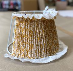 a lamp shade sitting on top of a table next to a white cloth covered floor