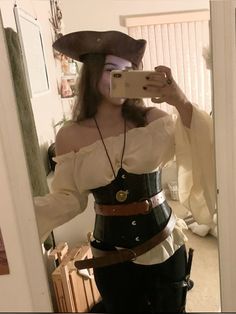 a woman taking a selfie in a mirror wearing a pirate costume and holding a camera