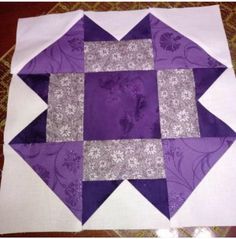 a purple and white patchwork quilt on the floor