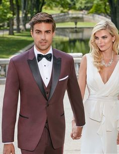 a man in a tuxedo and a woman in a white dress holding hands